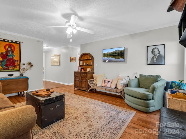 living room with a textured ceiling, crown molding, hardwood / wood-style flooring, and ceiling fan