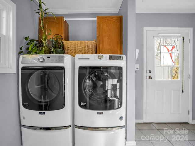 laundry area featuring crown molding, washing machine and dryer, light tile patterned floors, and cabinets