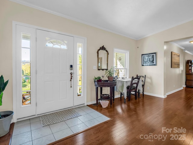 foyer with ornamental molding, baseboards, and wood finished floors