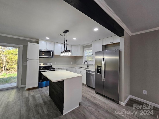 kitchen featuring appliances with stainless steel finishes, decorative light fixtures, white cabinets, and a center island