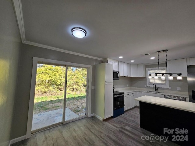 kitchen with ornamental molding, hardwood / wood-style floors, decorative light fixtures, white cabinetry, and appliances with stainless steel finishes