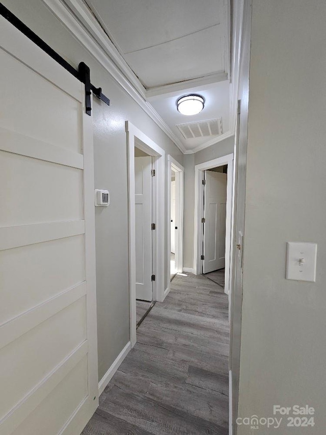 hallway with hardwood / wood-style floors, a barn door, and crown molding