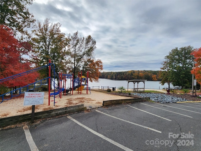 view of car parking with a water view and a playground