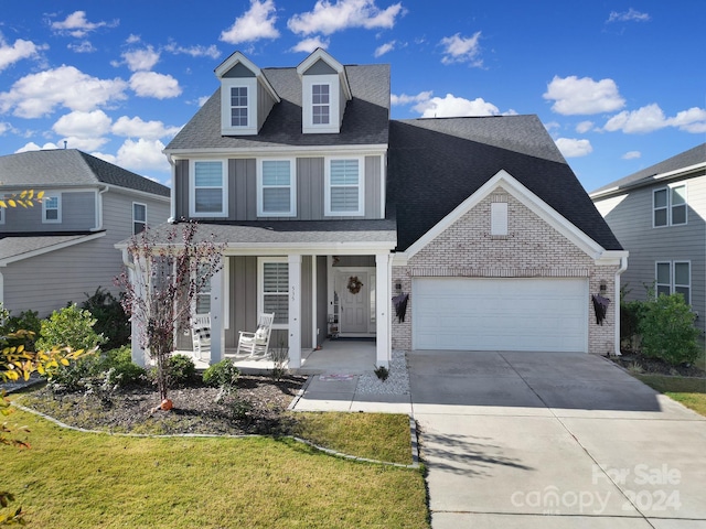 front of property featuring covered porch, a garage, and a front yard