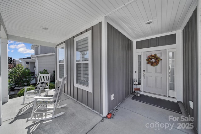 property entrance with board and batten siding and covered porch