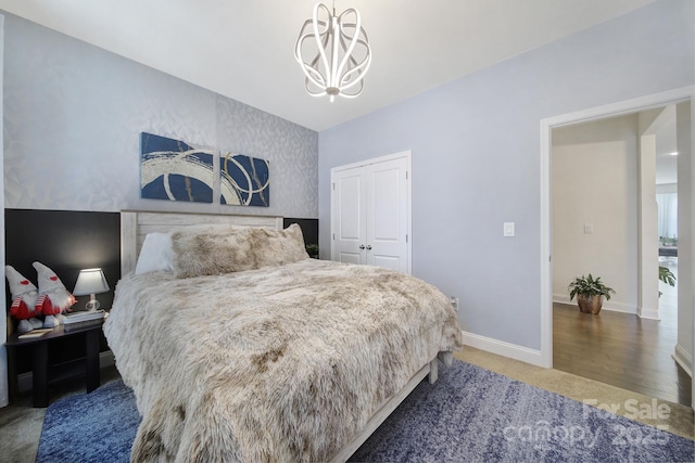 bedroom featuring a notable chandelier, baseboards, a closet, and wood finished floors