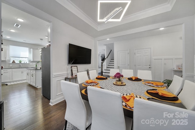 dining space featuring dark wood-style floors, wainscoting, visible vents, and crown molding