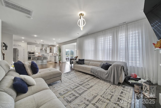 living area with light wood finished floors, visible vents, and recessed lighting