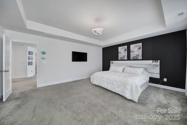 carpeted bedroom with a raised ceiling, visible vents, and baseboards