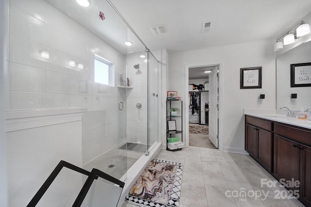 full bath featuring visible vents, a shower stall, vanity, and a spacious closet