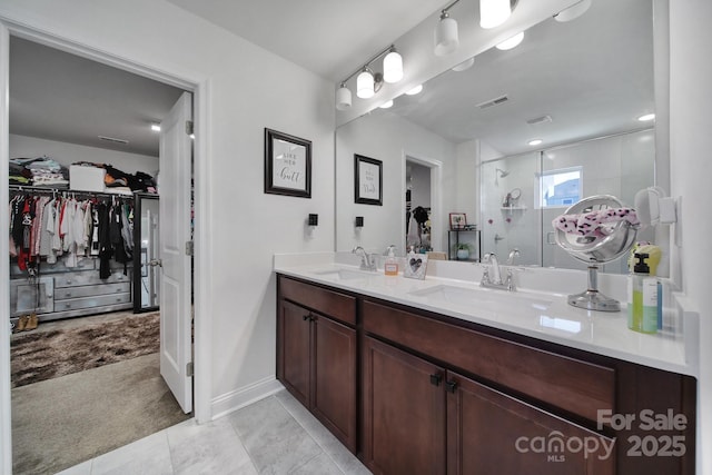 bathroom featuring a shower stall, a spacious closet, visible vents, and a sink