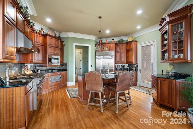 kitchen with light hardwood / wood-style flooring, a center island, built in appliances, crown molding, and decorative light fixtures