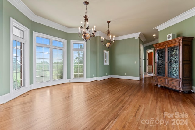 unfurnished dining area featuring ornamental molding, a wealth of natural light, light wood-type flooring, and an inviting chandelier