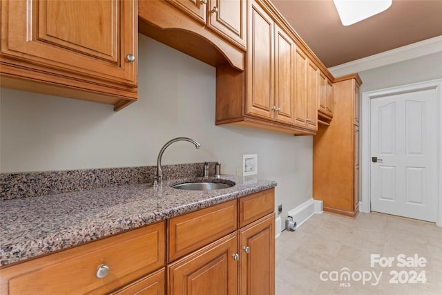 kitchen featuring ornamental molding, sink, and light stone countertops