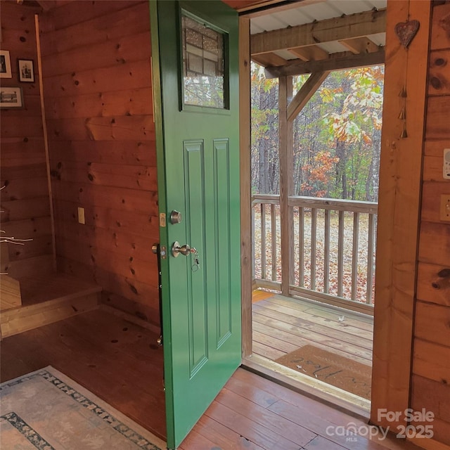 doorway featuring wood-type flooring and wooden walls