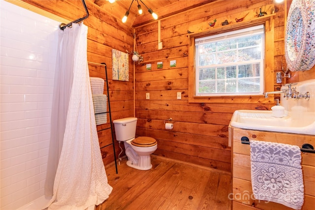 bathroom with hardwood / wood-style floors, wood walls, sink, walk in shower, and toilet