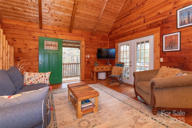 living room featuring french doors, wood walls, light hardwood / wood-style floors, and vaulted ceiling with beams