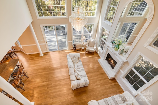 living room with a fireplace, a towering ceiling, light hardwood / wood-style flooring, and plenty of natural light