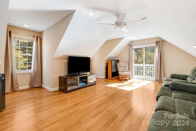 living room with a textured ceiling, light wood-type flooring, vaulted ceiling, and ceiling fan