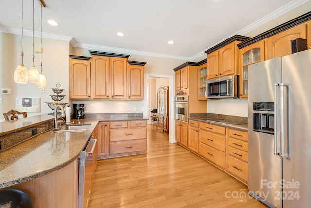 kitchen featuring appliances with stainless steel finishes, crown molding, sink, pendant lighting, and light hardwood / wood-style floors