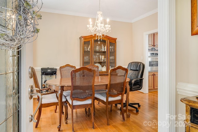 dining room with a notable chandelier, ornamental molding, and light hardwood / wood-style flooring