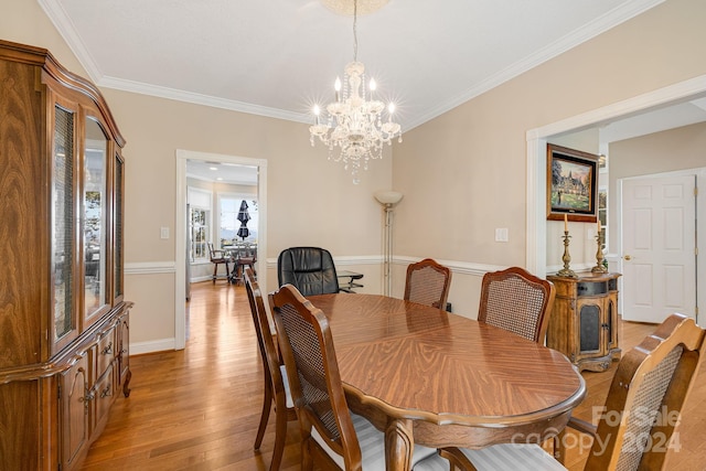 dining room featuring light hardwood / wood-style floors, ornamental molding, and an inviting chandelier