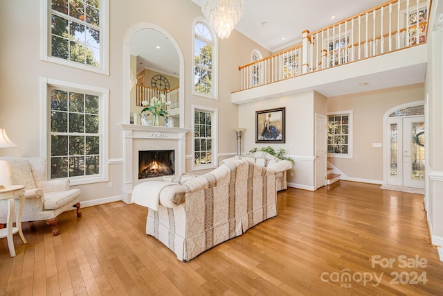 living room with a towering ceiling, light hardwood / wood-style floors, and a notable chandelier