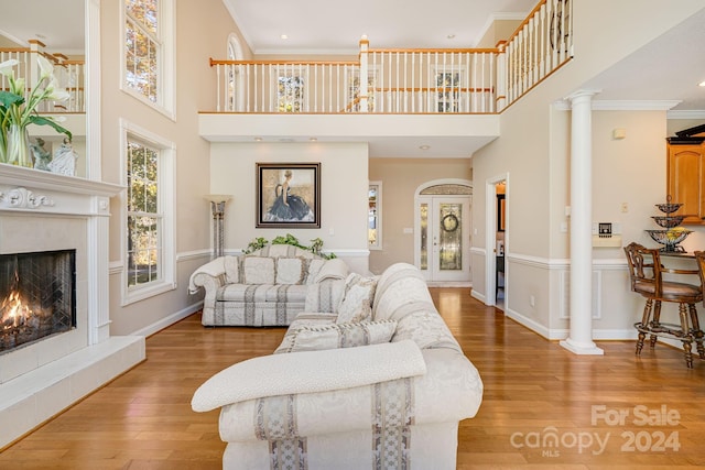 living room featuring hardwood / wood-style flooring, ornamental molding, a fireplace, and a high ceiling