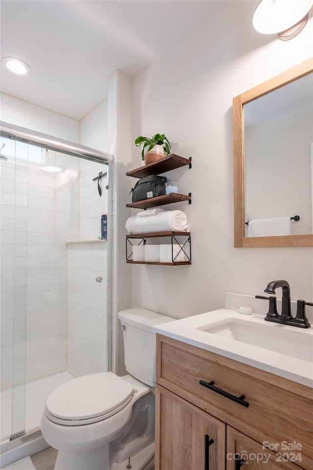 bathroom with a shower with door, vanity, and toilet