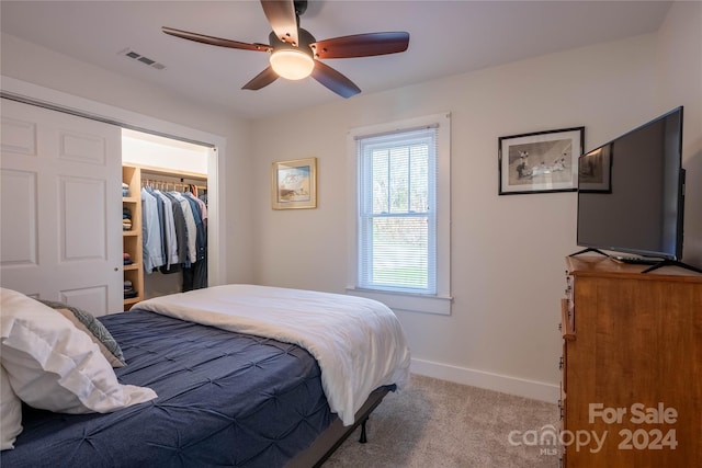 carpeted bedroom with ceiling fan, a walk in closet, and a closet