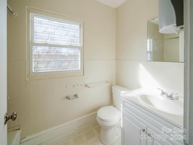 bathroom with vanity, toilet, tile walls, and a shower