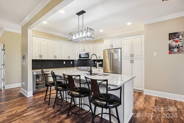 kitchen with dark wood-type flooring, appliances with stainless steel finishes, an island with sink, and white cabinets