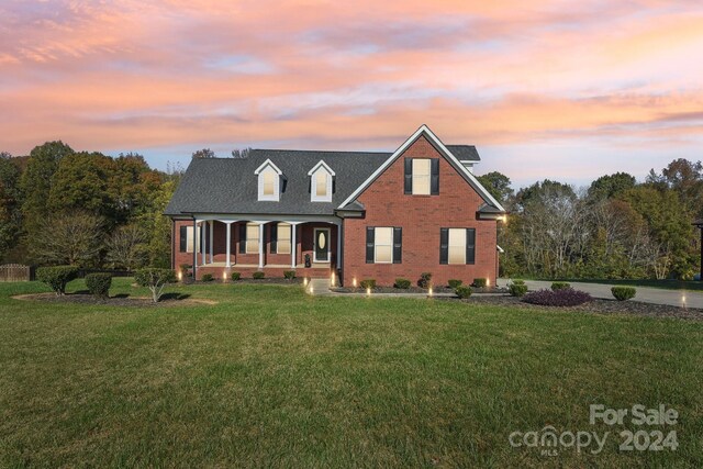 cape cod home featuring a yard