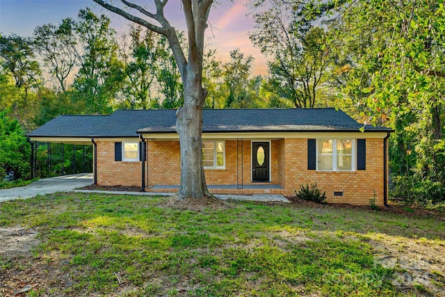 ranch-style home with a porch, a yard, and a carport