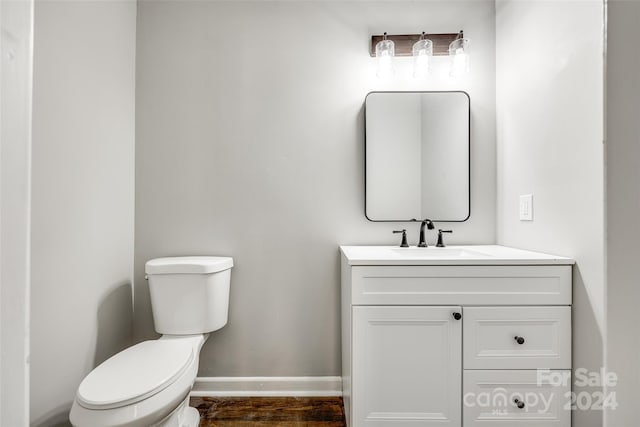 bathroom with toilet, hardwood / wood-style flooring, and vanity