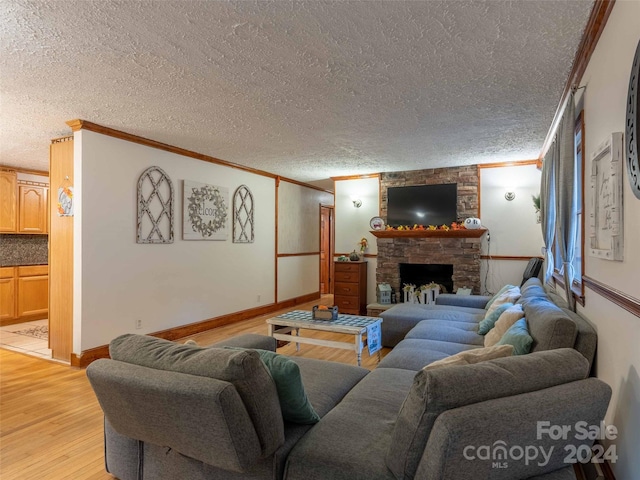 living room with crown molding, a fireplace, a textured ceiling, and light wood-type flooring