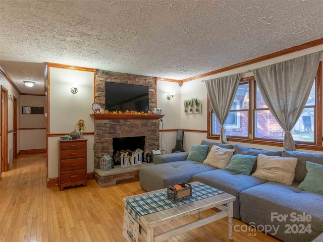 living room with light hardwood / wood-style floors, a textured ceiling, a fireplace, and ornamental molding