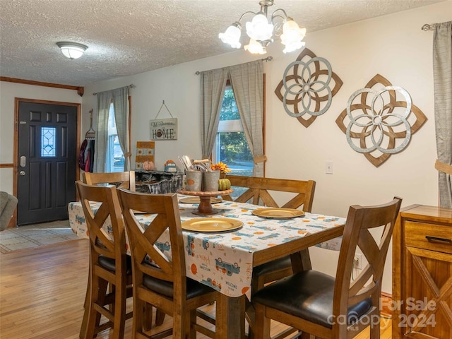 dining area with an inviting chandelier, light hardwood / wood-style flooring, and a textured ceiling