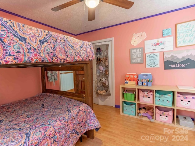 bedroom featuring a textured ceiling, hardwood / wood-style floors, a closet, ceiling fan, and crown molding