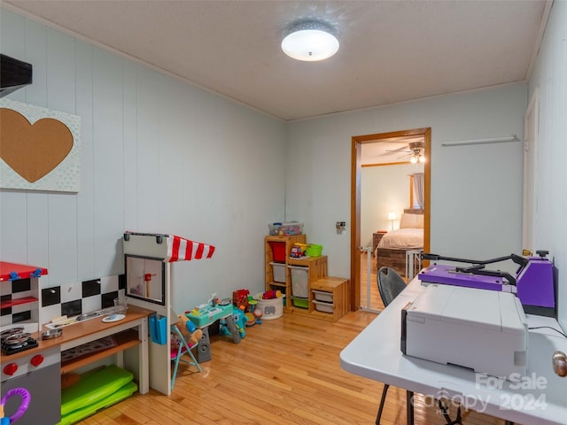 office with light hardwood / wood-style floors, ornamental molding, wood walls, and ceiling fan