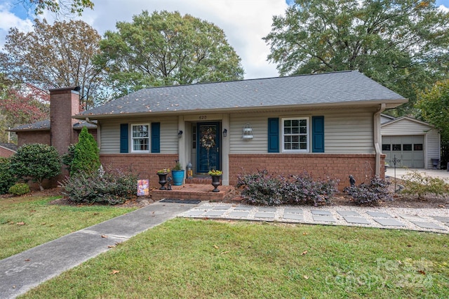 single story home featuring an outbuilding, a front lawn, and a garage