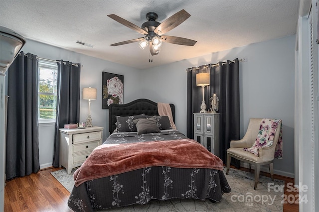 bedroom with ceiling fan, a textured ceiling, and light hardwood / wood-style flooring