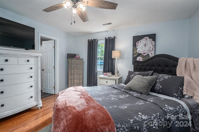 bedroom with ceiling fan, a textured ceiling, and light wood-type flooring