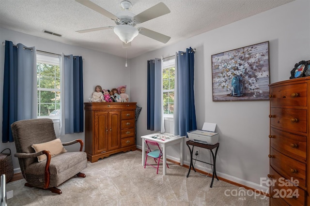 living area with light carpet, a textured ceiling, and ceiling fan