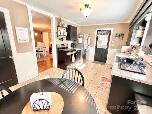 kitchen featuring crown molding, sink, light tile patterned floors, and stainless steel appliances