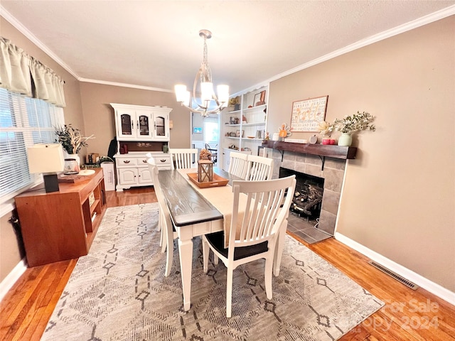 dining area featuring a tile fireplace, a wealth of natural light, an inviting chandelier, and hardwood / wood-style flooring