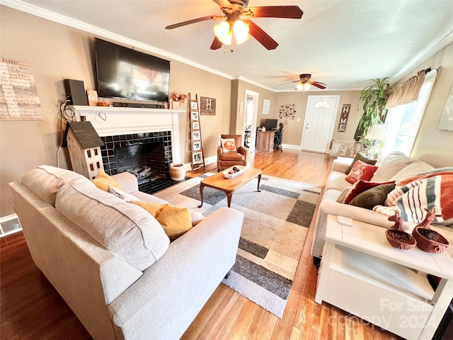 living room with a fireplace, ceiling fan, wood-type flooring, and ornamental molding