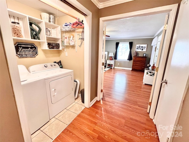 laundry area featuring independent washer and dryer, light wood-type flooring, and crown molding