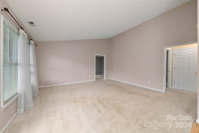 empty room with light colored carpet and vaulted ceiling