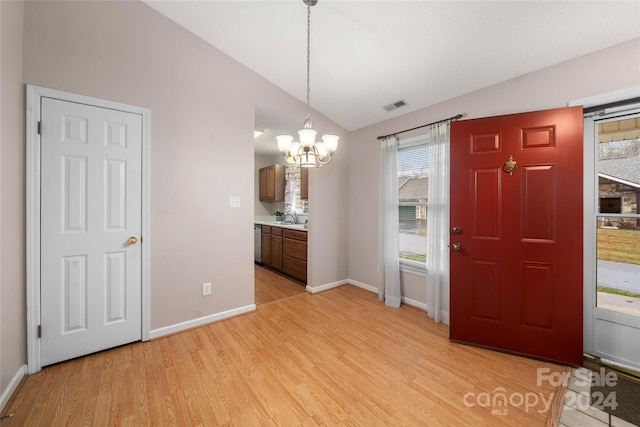 entrance foyer with sink, light wood-type flooring, lofted ceiling, and a notable chandelier